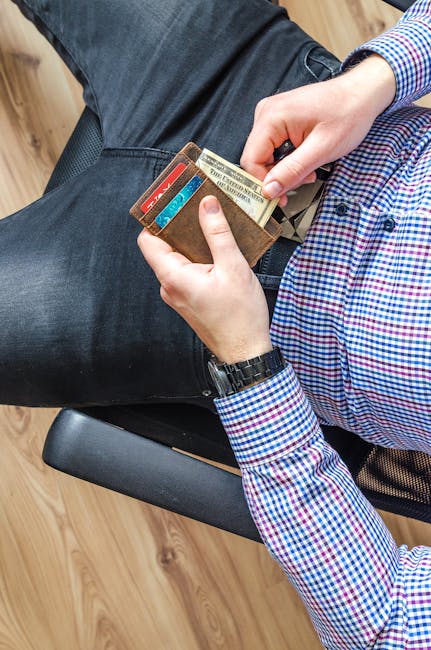 Close-up of a man in casual attire holding a wallet and checking his credit cards indoors.