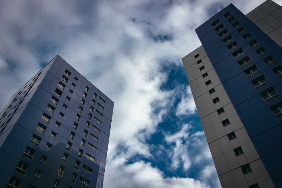 Low angle view of modern skyscrapers with a cloudy backdrop, emphasizing urban architecture.